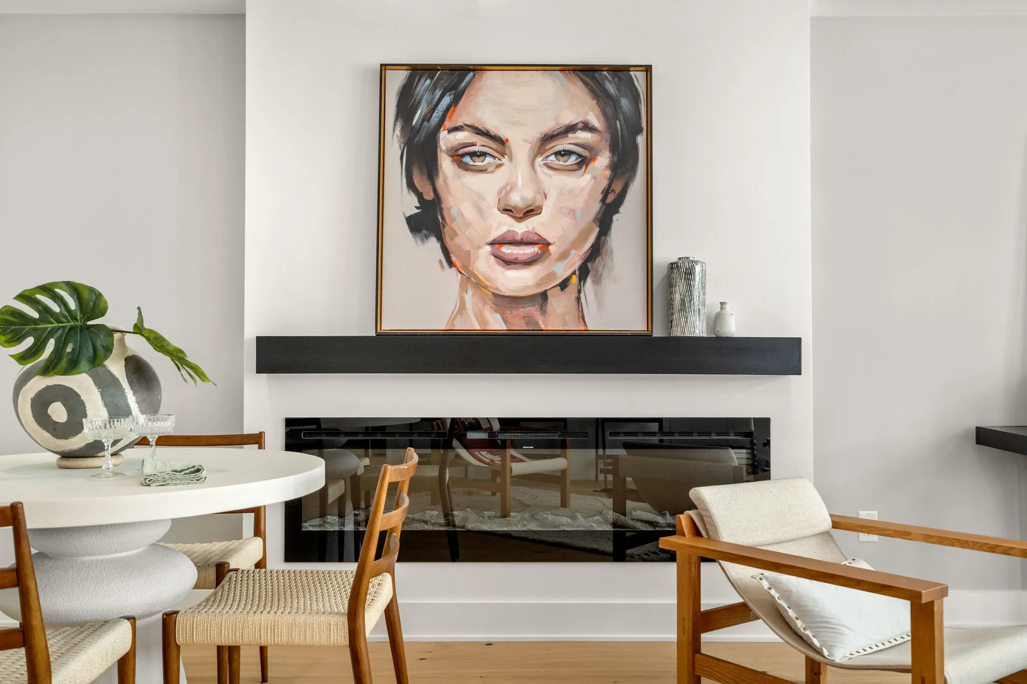 A modern open-concept living and dining room features hardwood floors, a fireplace, and large windows.